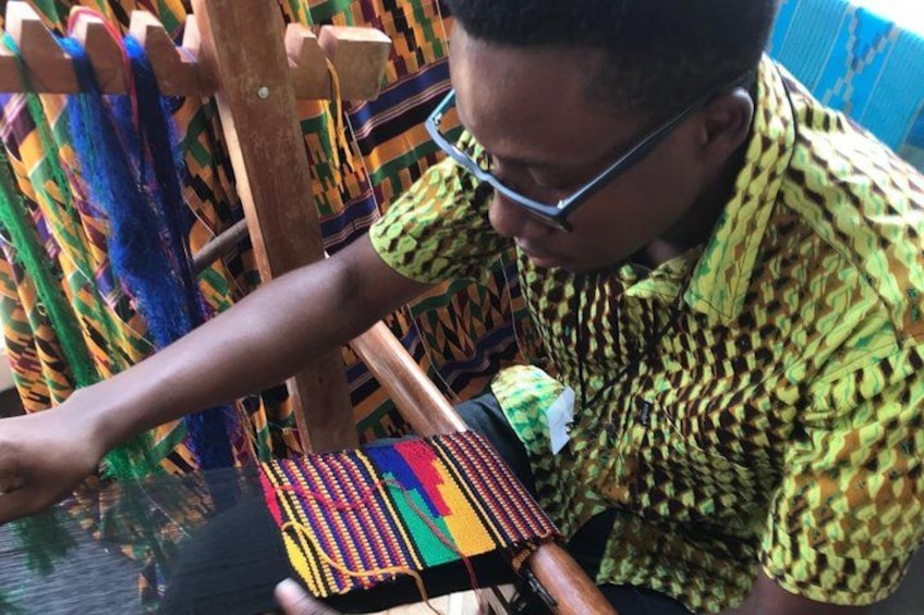 A person weaving colorful fabric on a wooden loom. 4