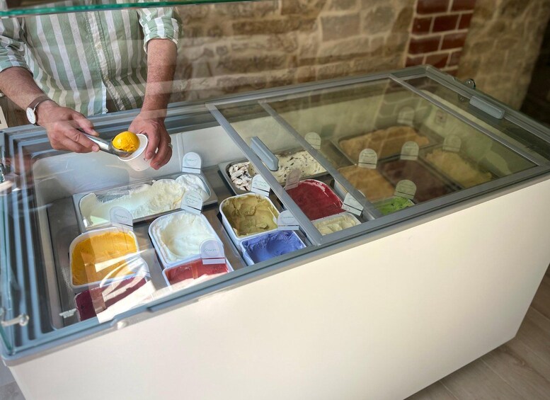 Une personne qui puise de la glace dans un récipient en verre contenant différentes saveurs. 4