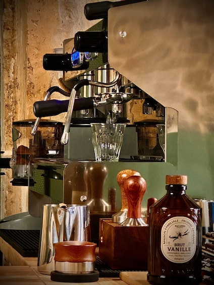 Une machine à café, un verre, une cuillère en bois et une bouteille de sirop Vanille Brut. 3