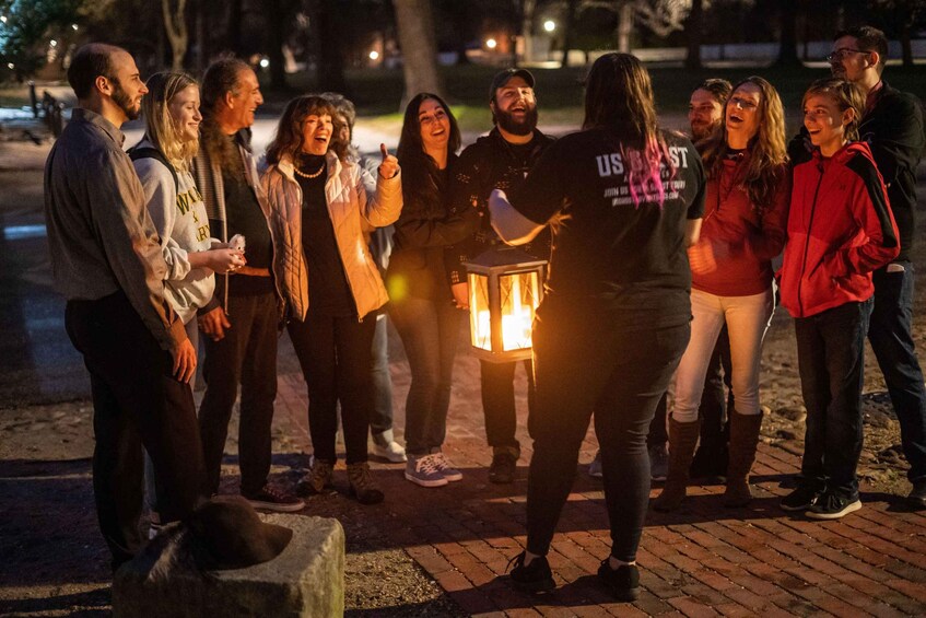 A group of people gathered around a person holding a lantern. 2