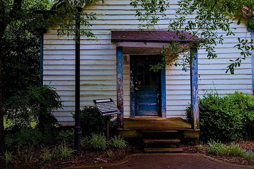 A rustic building with a blue door, surrounded by greenery and a brick pathway. 3