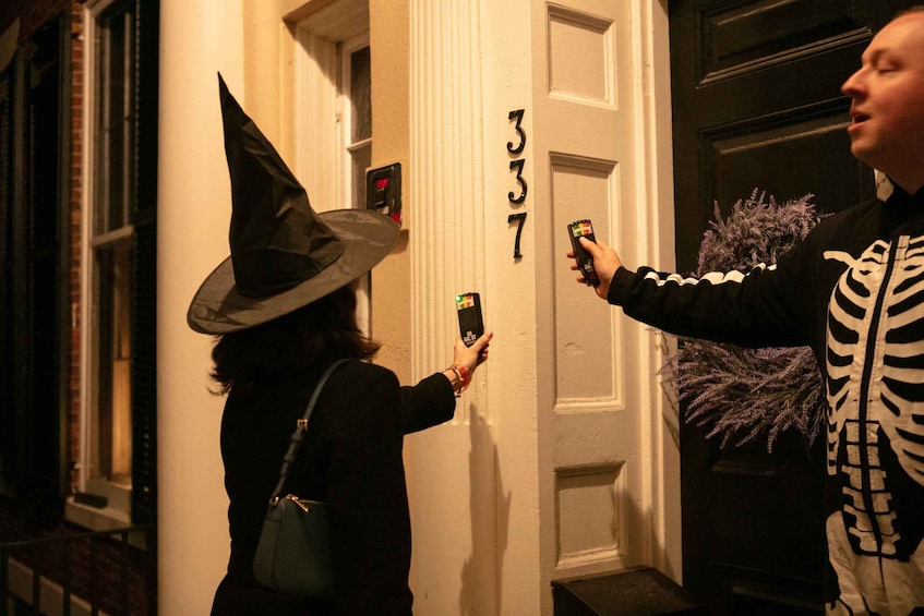 A person in a witch hat taking a photo with a smartphone at a door marked '337'. 4