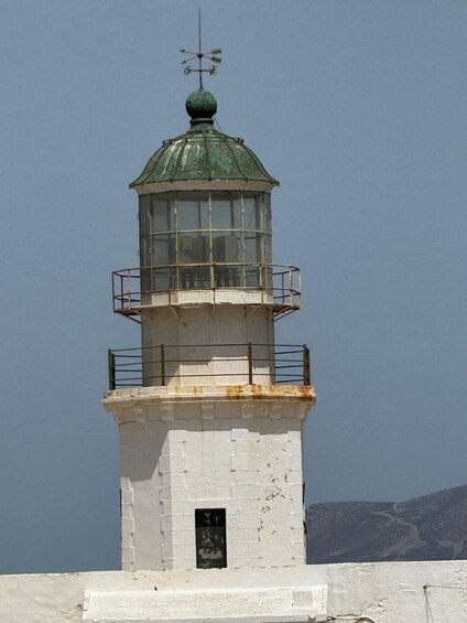A lighthouse with a green dome and a weather vane on top. 3