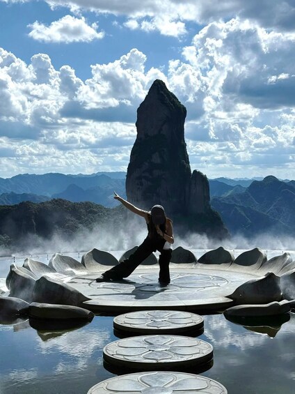 A person performing a yoga pose on floating platforms with a mountainous landscape in the background. 2