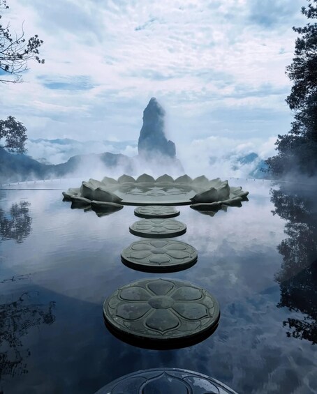 A tranquil lake with lotus-shaped stepping stones leading to a misty mountain peak. 1