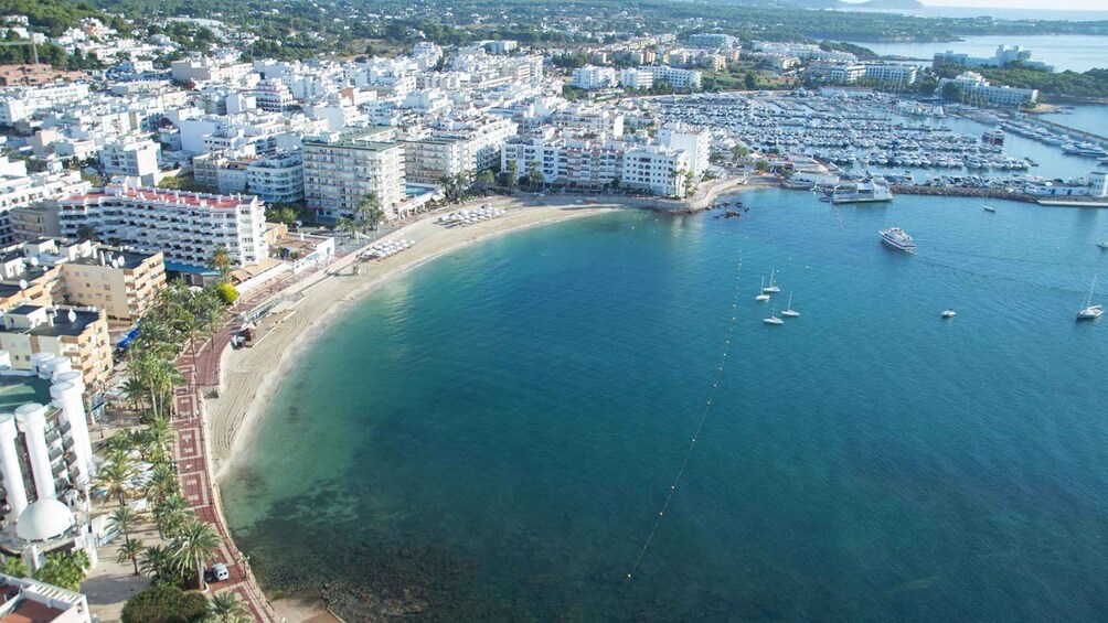 A coastal cityscape with a clear blue bay, numerous buildings, and a marina with boats. 4