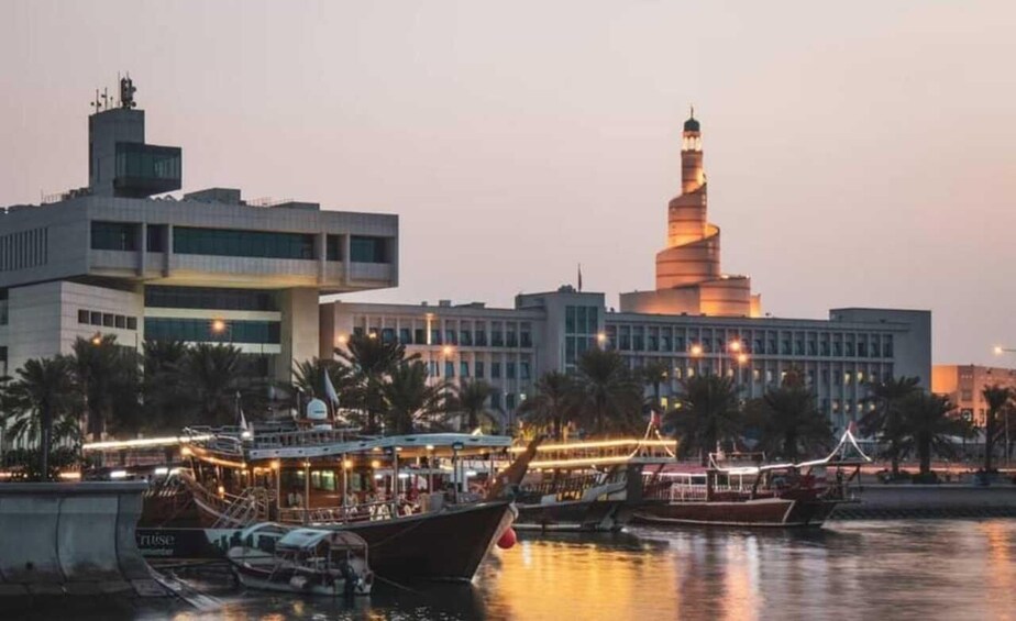 A waterfront with boats docked, a modern building, and a prominent spiral tower. 5