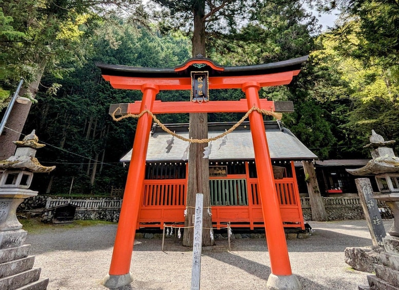 A traditional Japanese torii gate with a red frame and a black roof, surrounded by trees and stone lanterns. 3