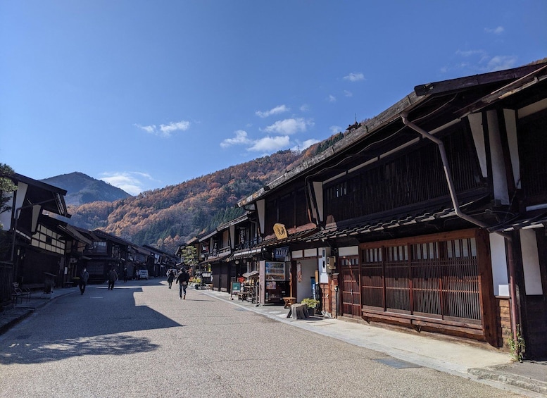 A traditional street with wooden buildings, a clear sky, and a mountain in the background. 1