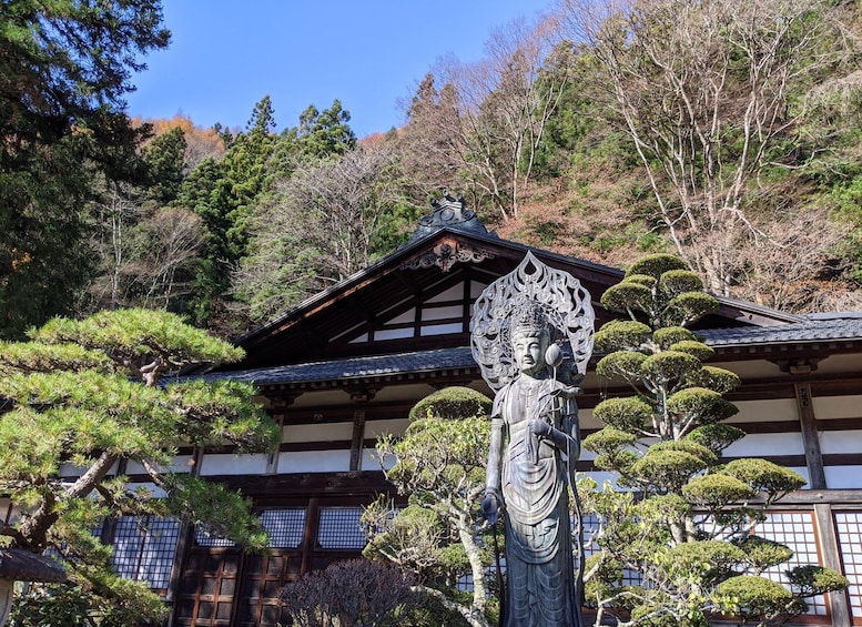 A traditional Japanese building with a statue in front. 5