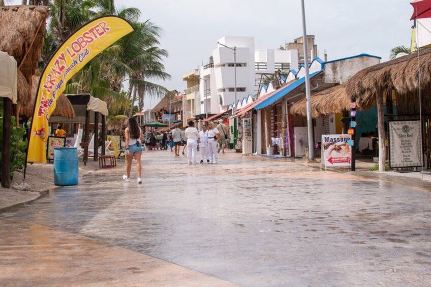 A wet street with a yellow archway, palm trees, and buildings. 3