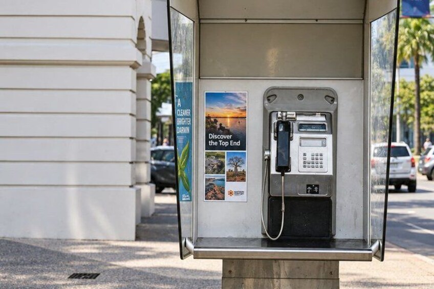 A public phone booth with a poster advertising a cleaner, brighter city. 4