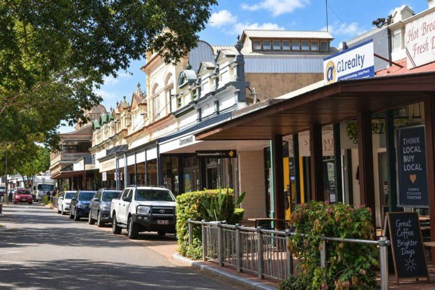 A street lined with shops, including a real estate office, and parked cars. 2