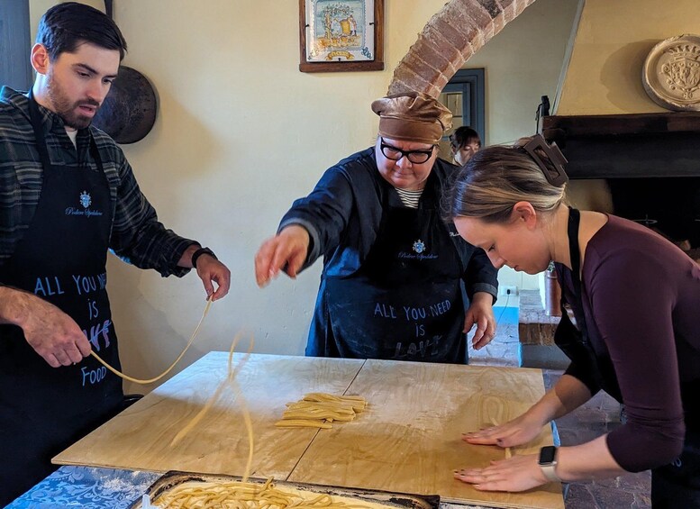 Tres personas preparando comida, con pasta sobre una mesa de madera. 3