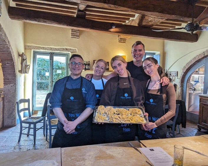 Un grupo de personas con delantales sostienen una bandeja de comida, en un interior rústico con vigas a la vista y paredes de ladrillo. 1
