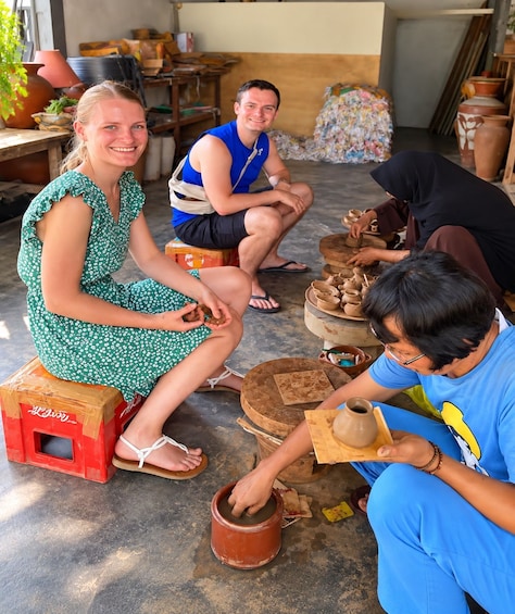 People engaged in pottery making, seated on stools, with clay pots and tools on the floor. 1