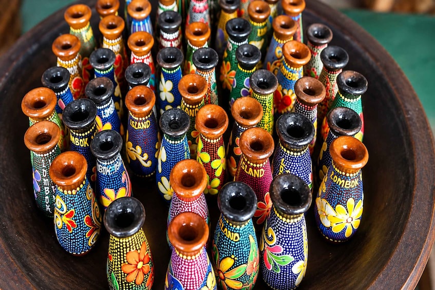 A collection of colorful, intricately decorated vases arranged on a wooden tray. 3