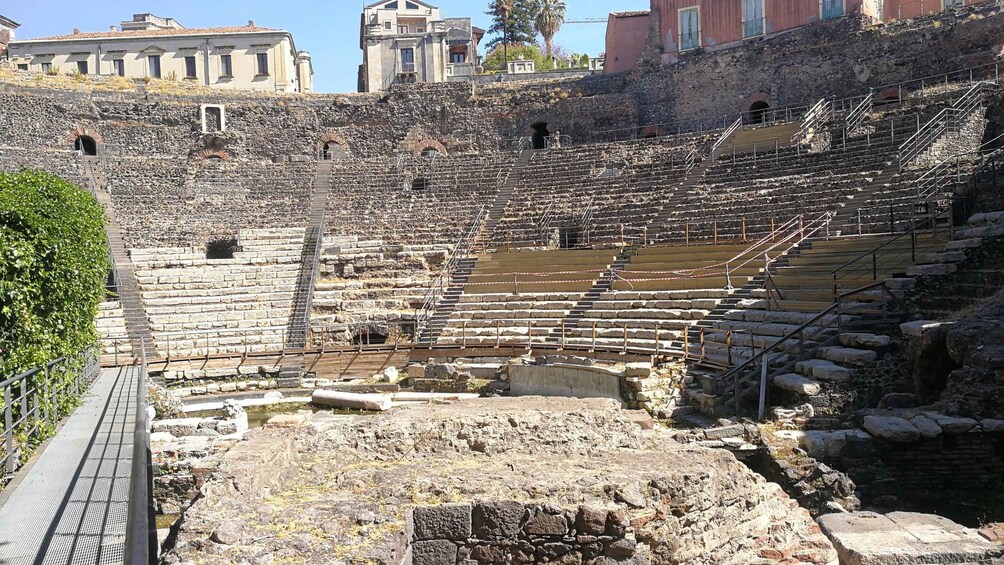 An ancient amphitheater with stone steps and a central stage. 3