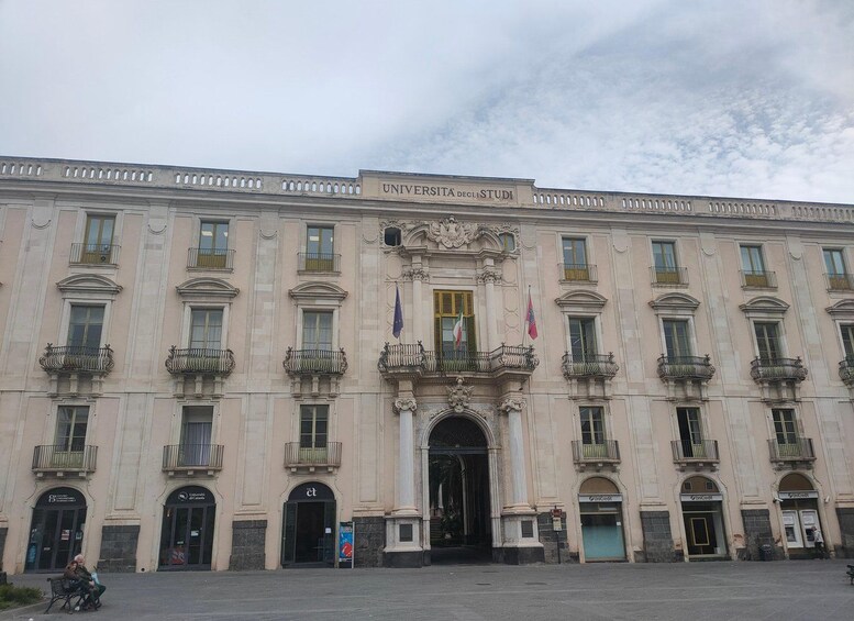 A historic building with ornate balconies and flags, labeled 'Universita degli Studi.' 5
