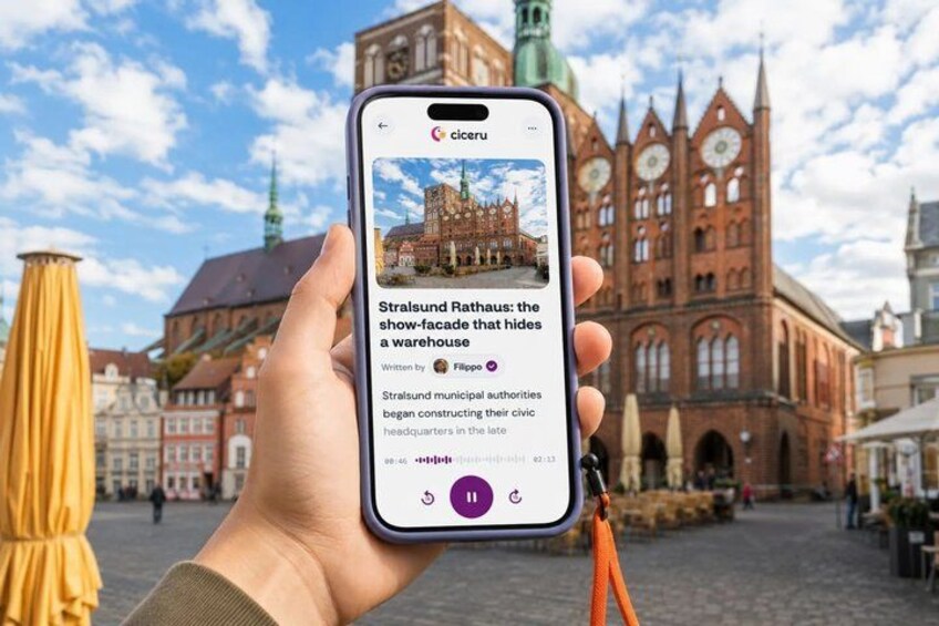 A hand holding a smartphone displaying a photo of a historic building with a caption about it. 1