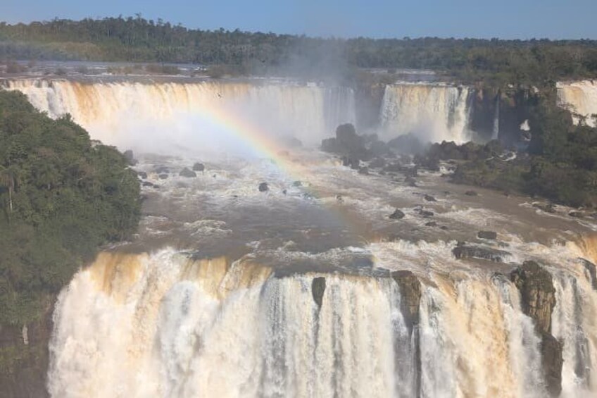A large waterfall with a rainbow, surrounded by dense greenery. 2