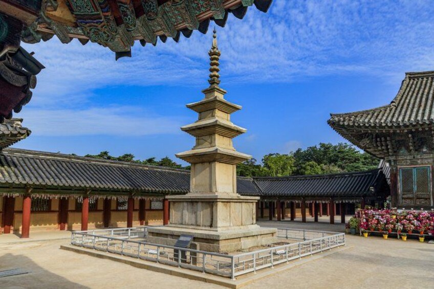A traditional Korean temple with a pagoda, stone lanterns, and potted flowers. 5