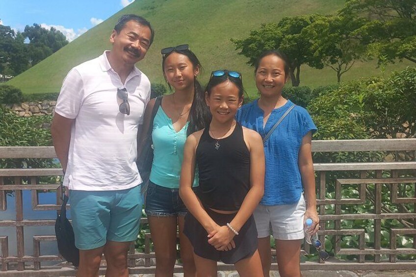 A group of people standing on a bridge with a hilly landscape in the background. 2