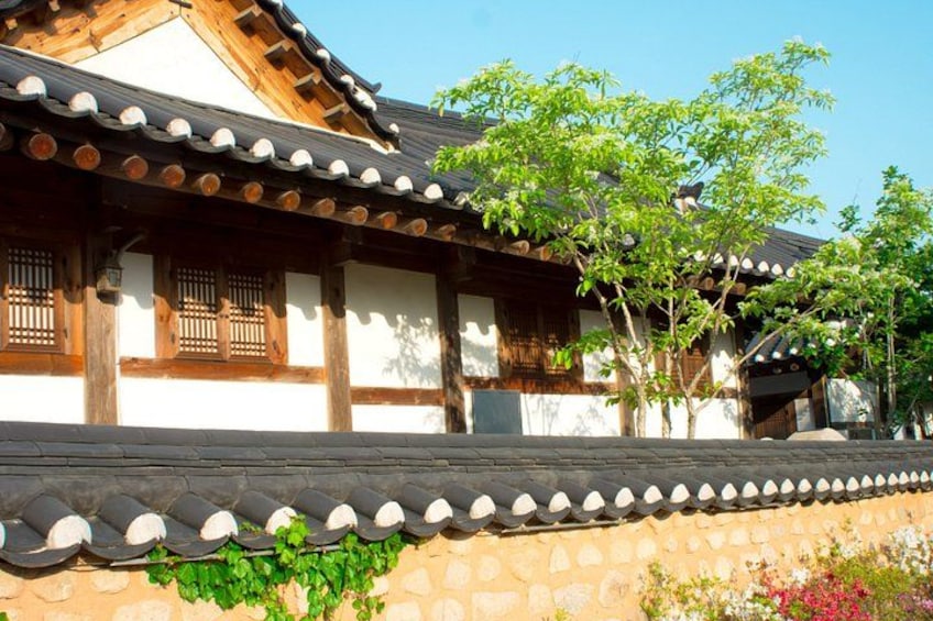 Un edificio japonés tradicional con vigas de madera, tejado de tejas y un muro de piedra con plantas. 4