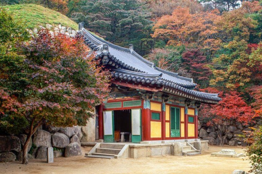 A traditional Korean temple with a curved roof, surrounded by autumn-colored trees. 4