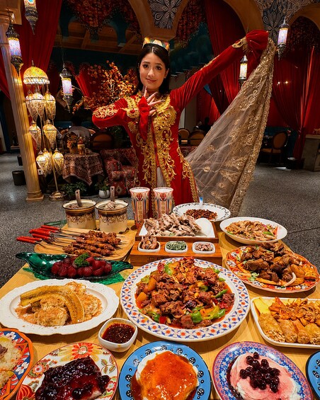 A person in traditional attire surrounded by a variety of dishes and food items. 1