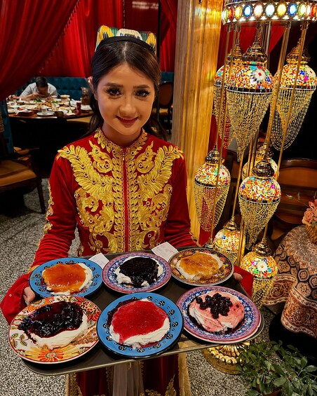 A person in traditional attire holding plates of desserts. 2