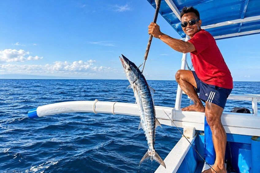 A person on a boat holding a fish. 5