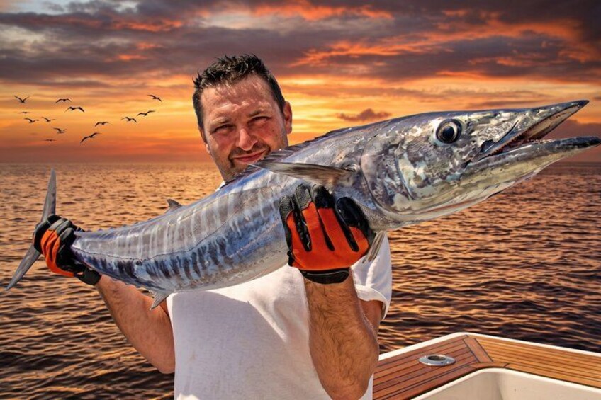 A person holding a large fish on a boat with a sunset in the background. 5