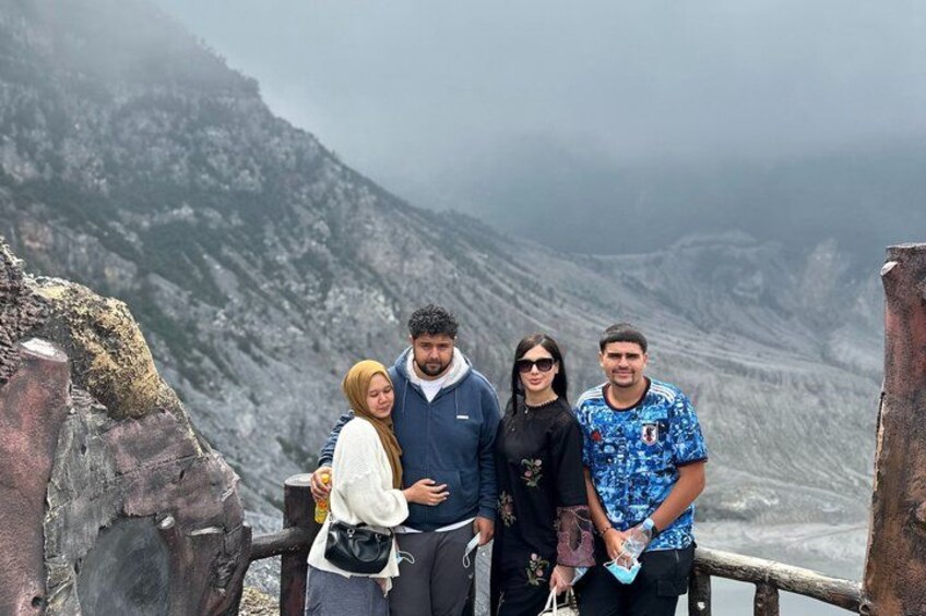 A group of people standing on a rocky ledge with a mountainous landscape in the background. 1