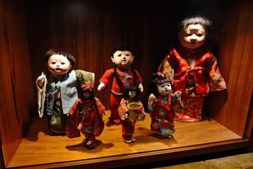 A display of traditional dolls in a wooden case. 4