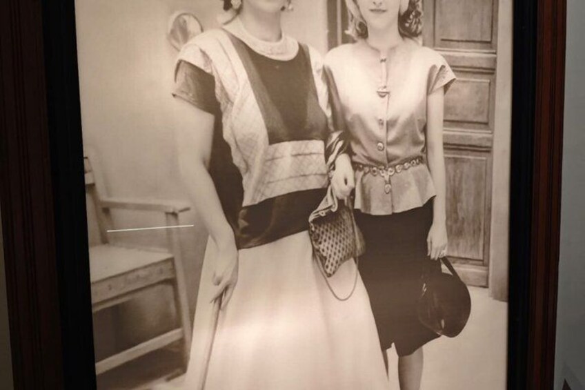 A vintage photograph of two women in period clothing, one holding a handbag. 3