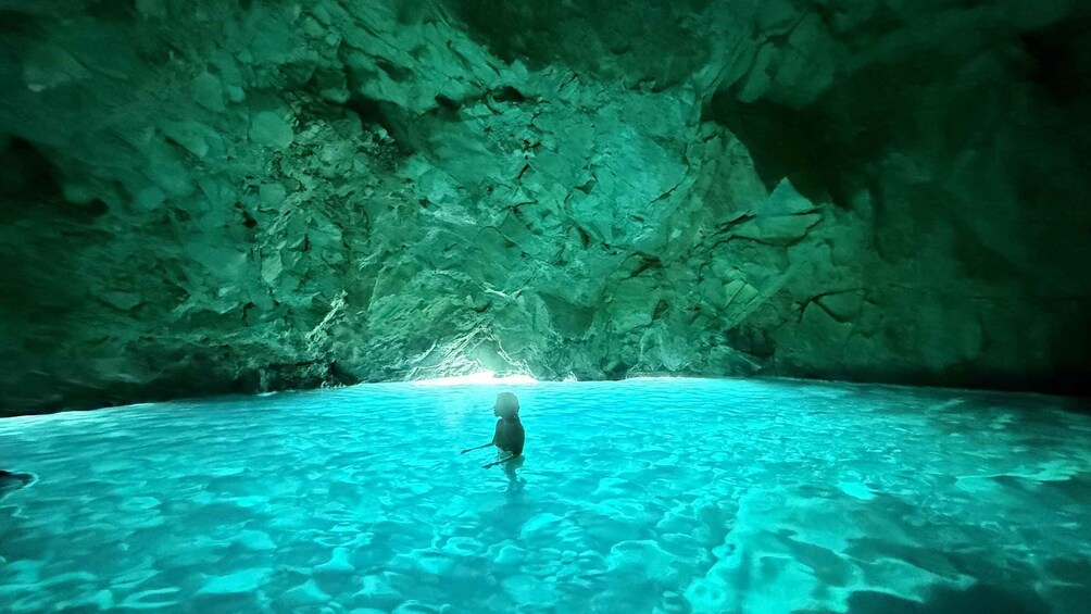 A cave with clear water and a person standing in the middle. 2