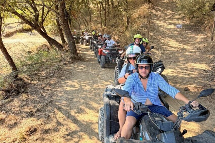 A group of people riding ATVs on a dirt path surrounded by trees. 5
