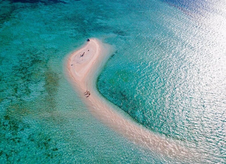 Et luftbillede af en kigsformet sandstrand med krystalklart turkisblåt vand. 2