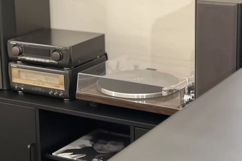 A turntable with a record on it, a cassette player, and a photo frame on a shelf. 3