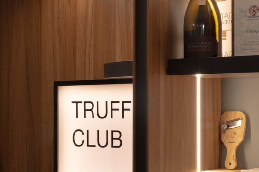 A wooden interior with a sign reading 'TRUFF CLUB' and a bottle of wine on a shelf. 4