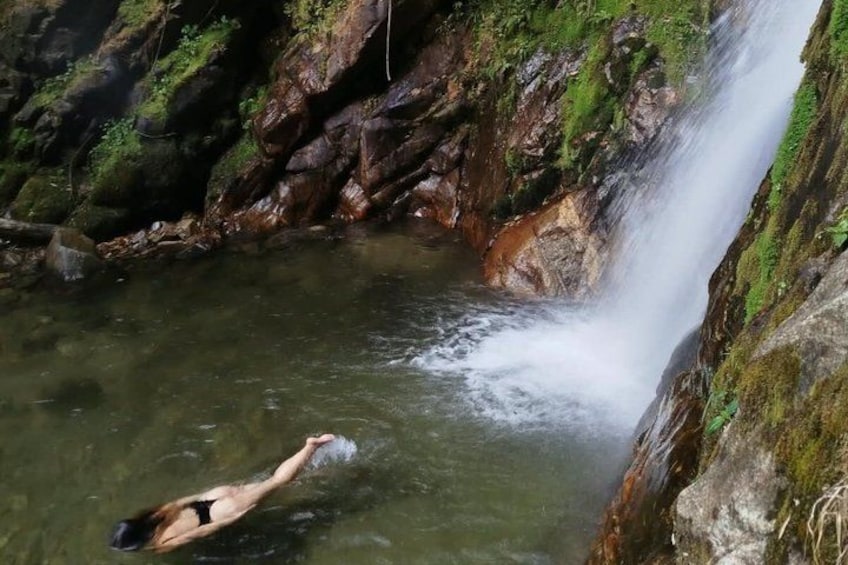 A person swimming in a natural pool with a waterfall. 3