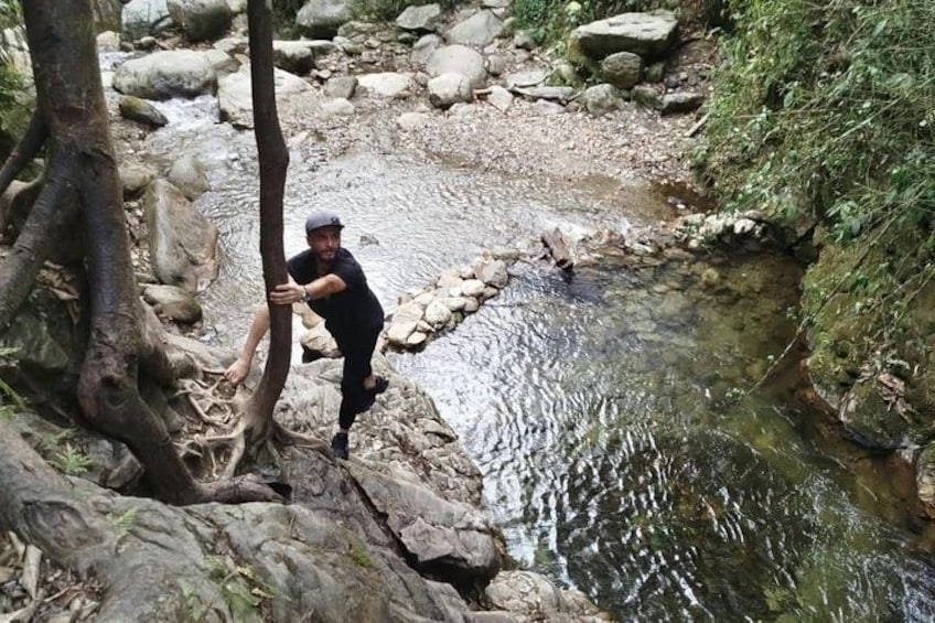 A person climbing a rocky terrain near a stream. 4