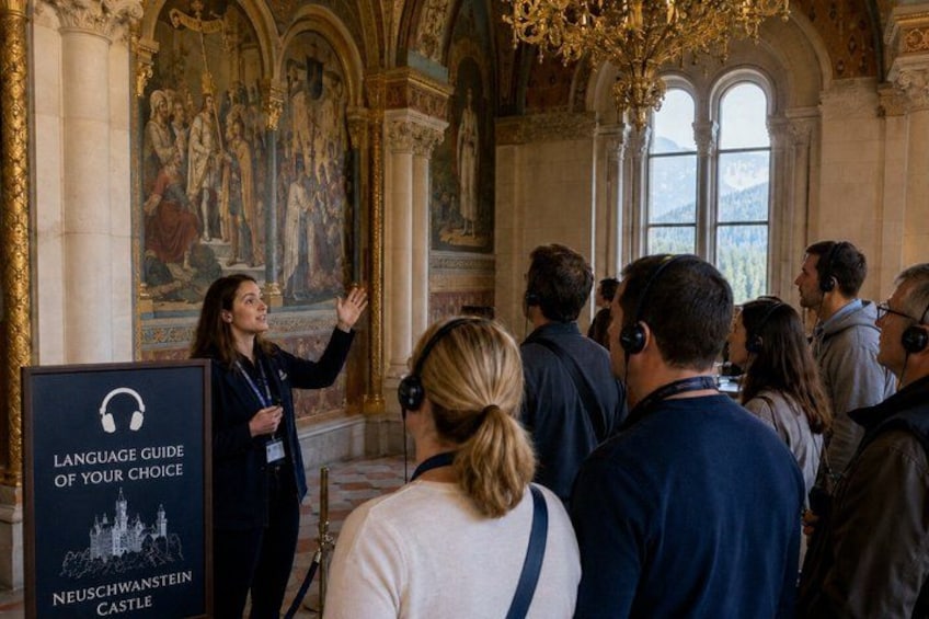 A group of people in a grand hall with a speaker presenting at a podium. 4