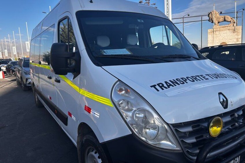 A white van with 'TRANSPORTETURISMO' on the side parked in a lot with other vehicles. 4