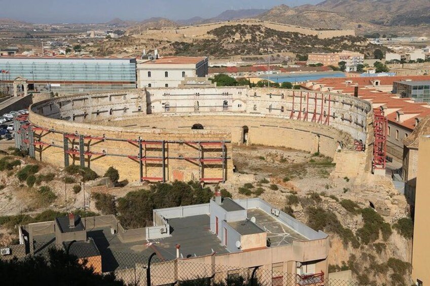 An ancient amphitheater with a modern building adjacent to it. 3