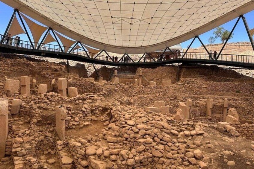 An archaeological site with exposed ruins and a large tent-like structure overhead. 4