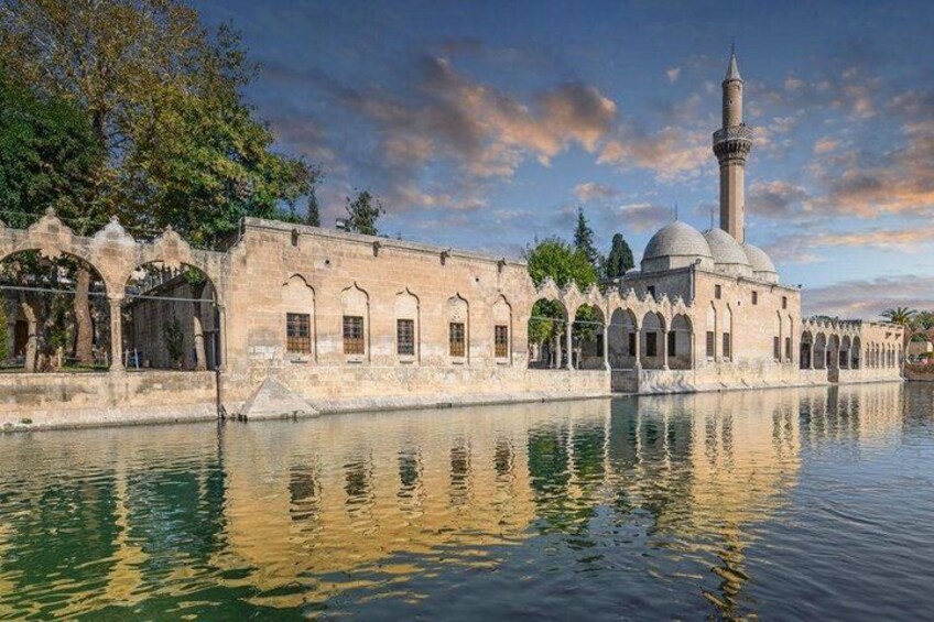 A historic building with arches and a tower, reflecting in a calm body of water. 3