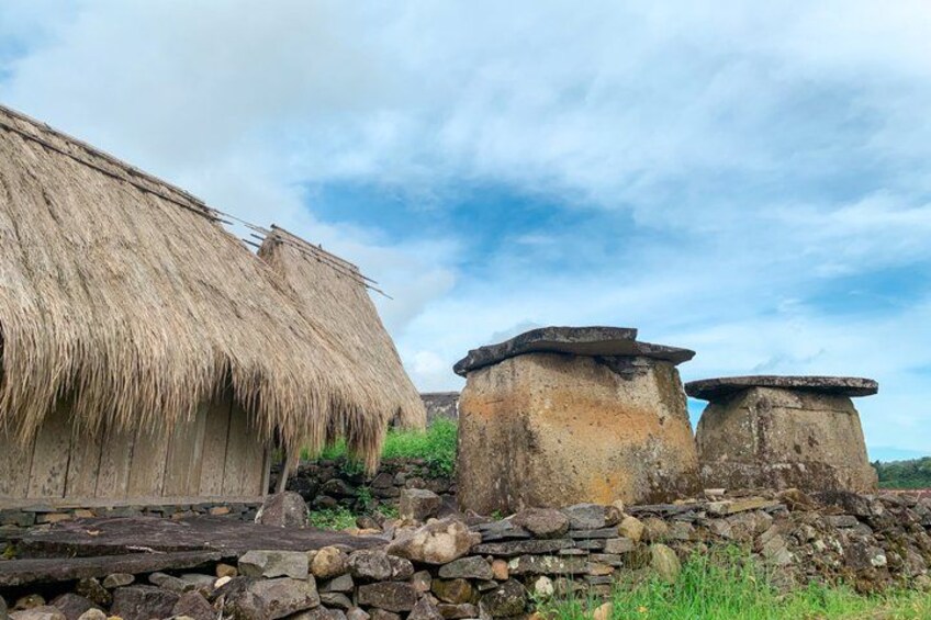 A traditional thatched-roof hut, stone structures, and a stone wall. 2
