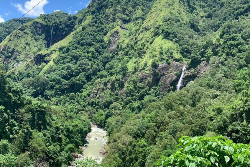 A river flowing through a lush green valley with a waterfall and dense forest. 3